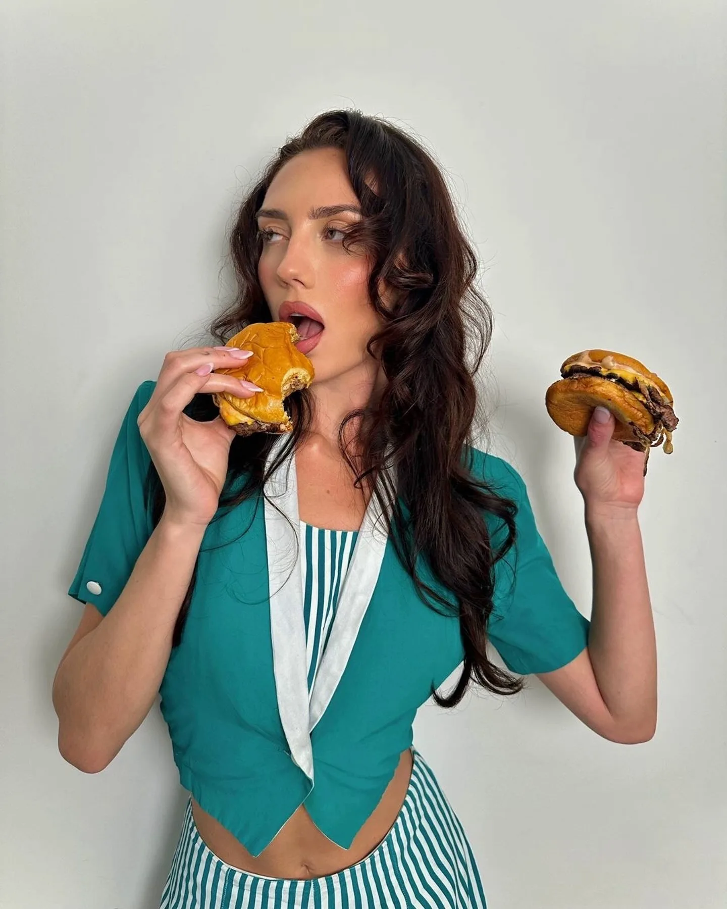 Žena jede hamburgere s mesom.